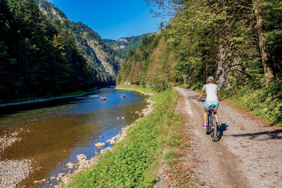 Young woman cycling along Dunajec river on sunny autumn day, Pieniny Mountains, Poland